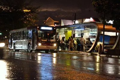 Foto ilustrativa: Ônibus em rua molhada pela chuva, à noite