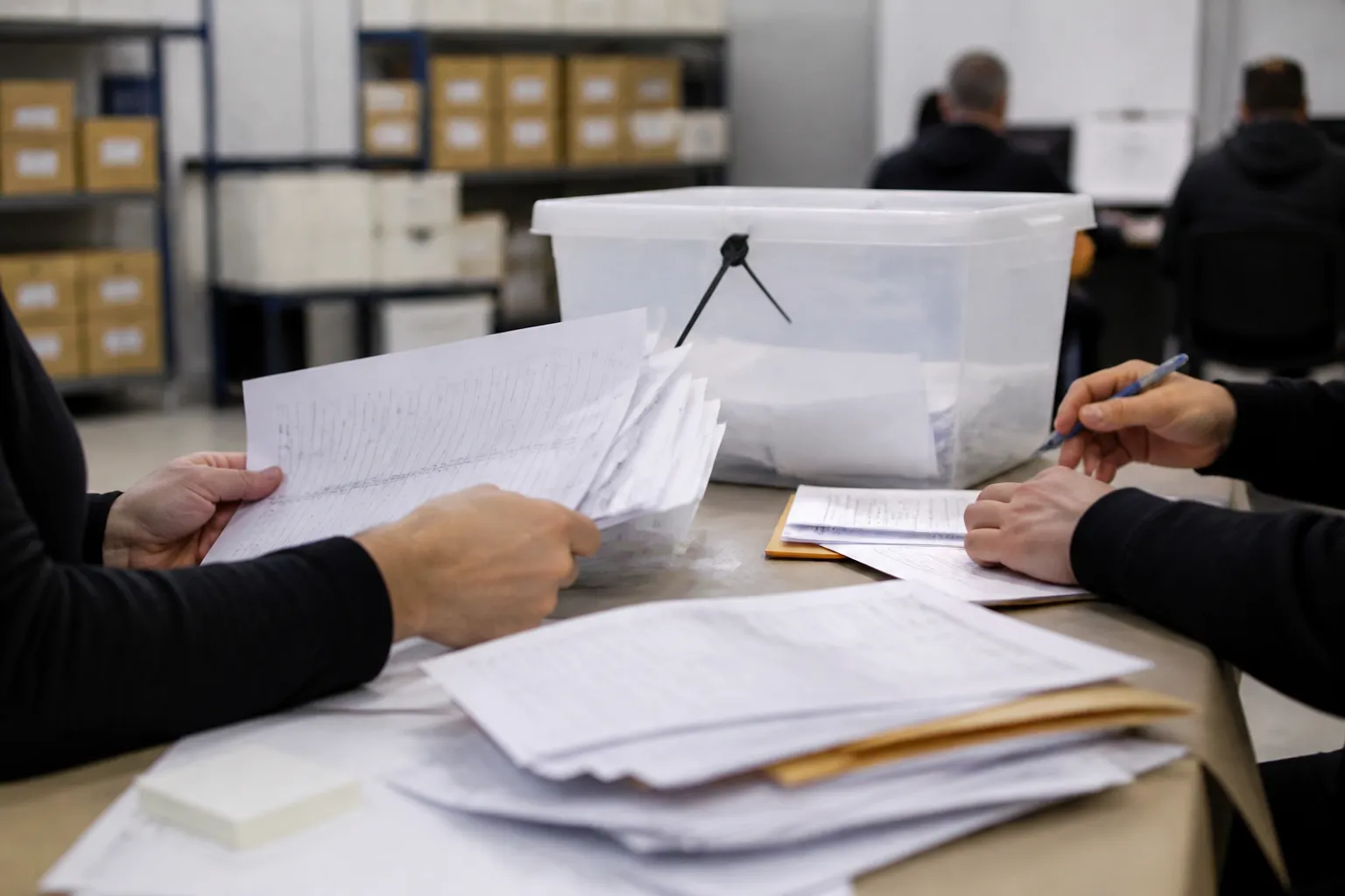 Imagem gerada por IA: Mesa institucional com documentos eleitorais e urna ao fundo
